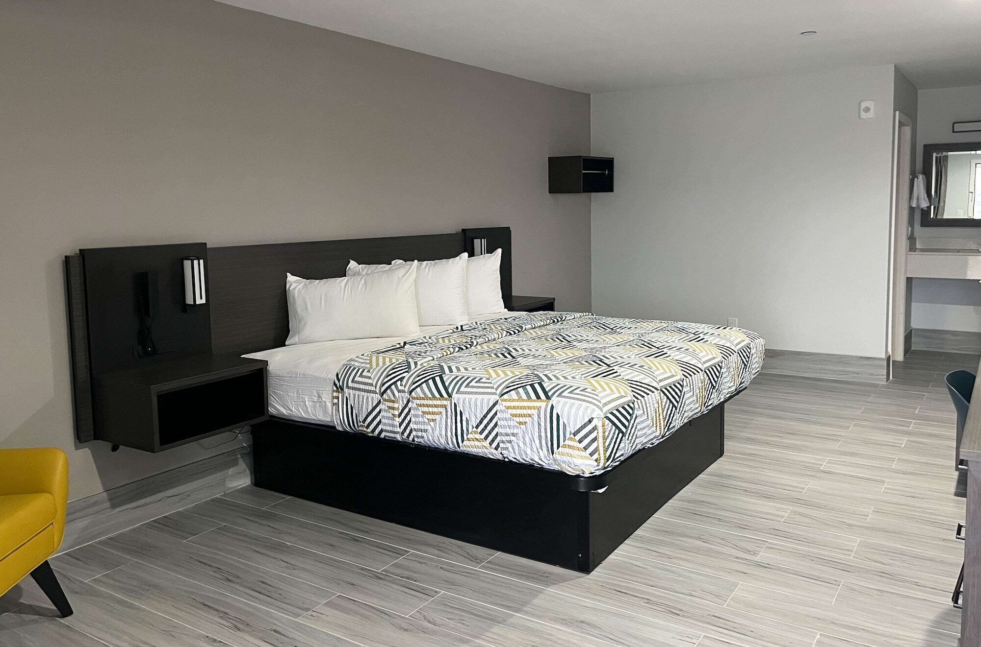 A modern bedroom with a large bed, dark headboard, and a small bedside table.