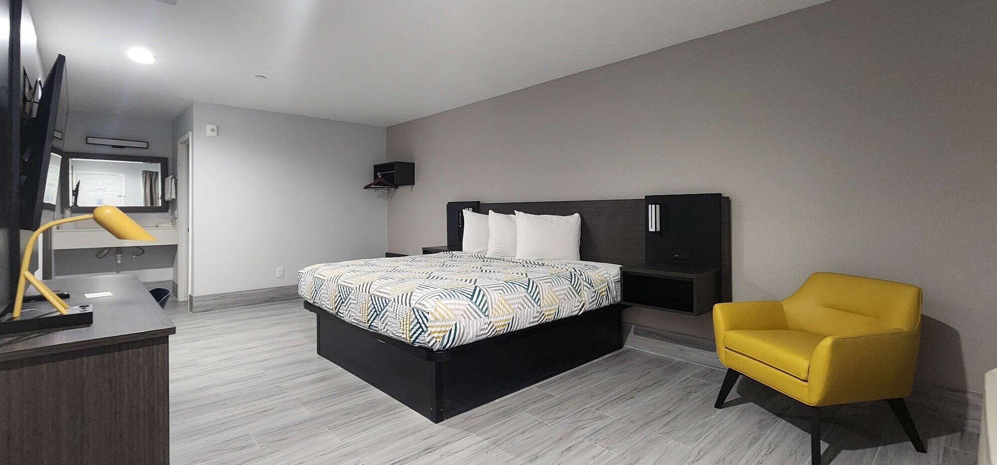 Una habitación de hotel moderna con cama, escritorio, silla y televisor.