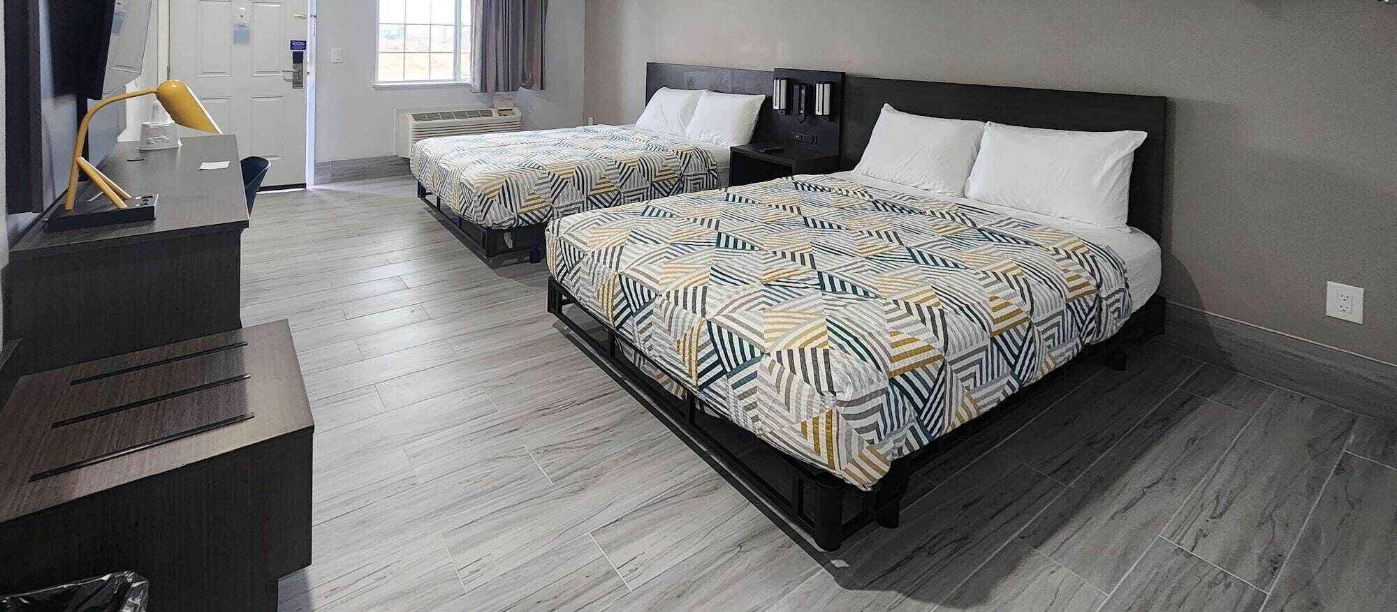A hotel room with two beds, a desk, and a chair.