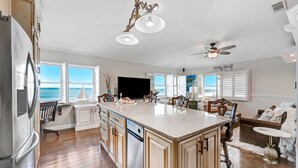 A spacious kitchen with a large island, wooden cabinets, and a view of the ocean. - Spectacular direct ocean front condo with amazing views of the Atlantic (Satellite Beach)