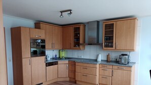 Una cocina moderna con armarios de madera, horno empotrado, cafetera y campana extractora de acero inoxidable.