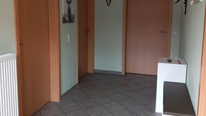 Un pasillo con dos puertas de madera, un radiador y un armario blanco con un objeto rojo encima.