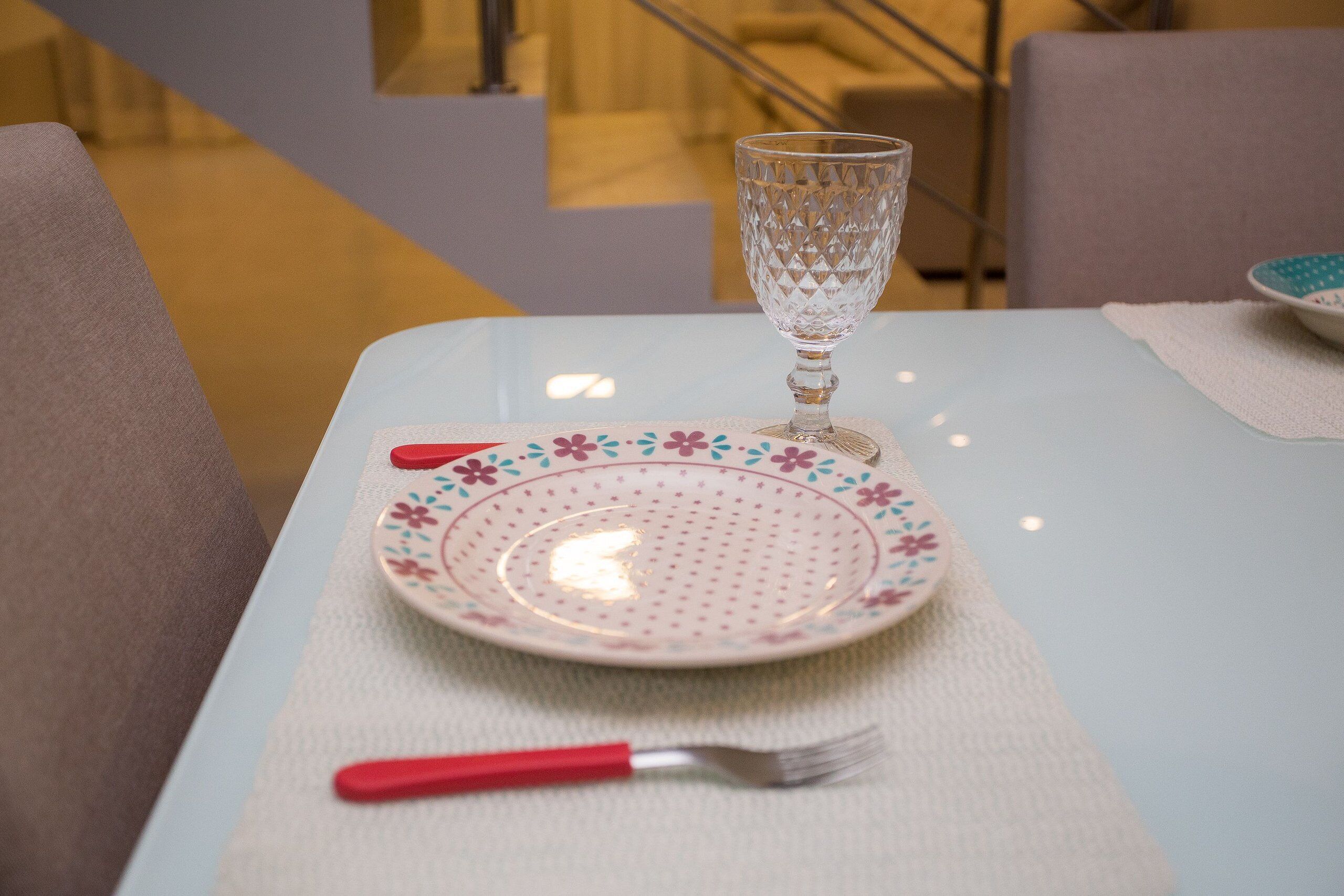A dining table with a plate, a glass, and a fork.