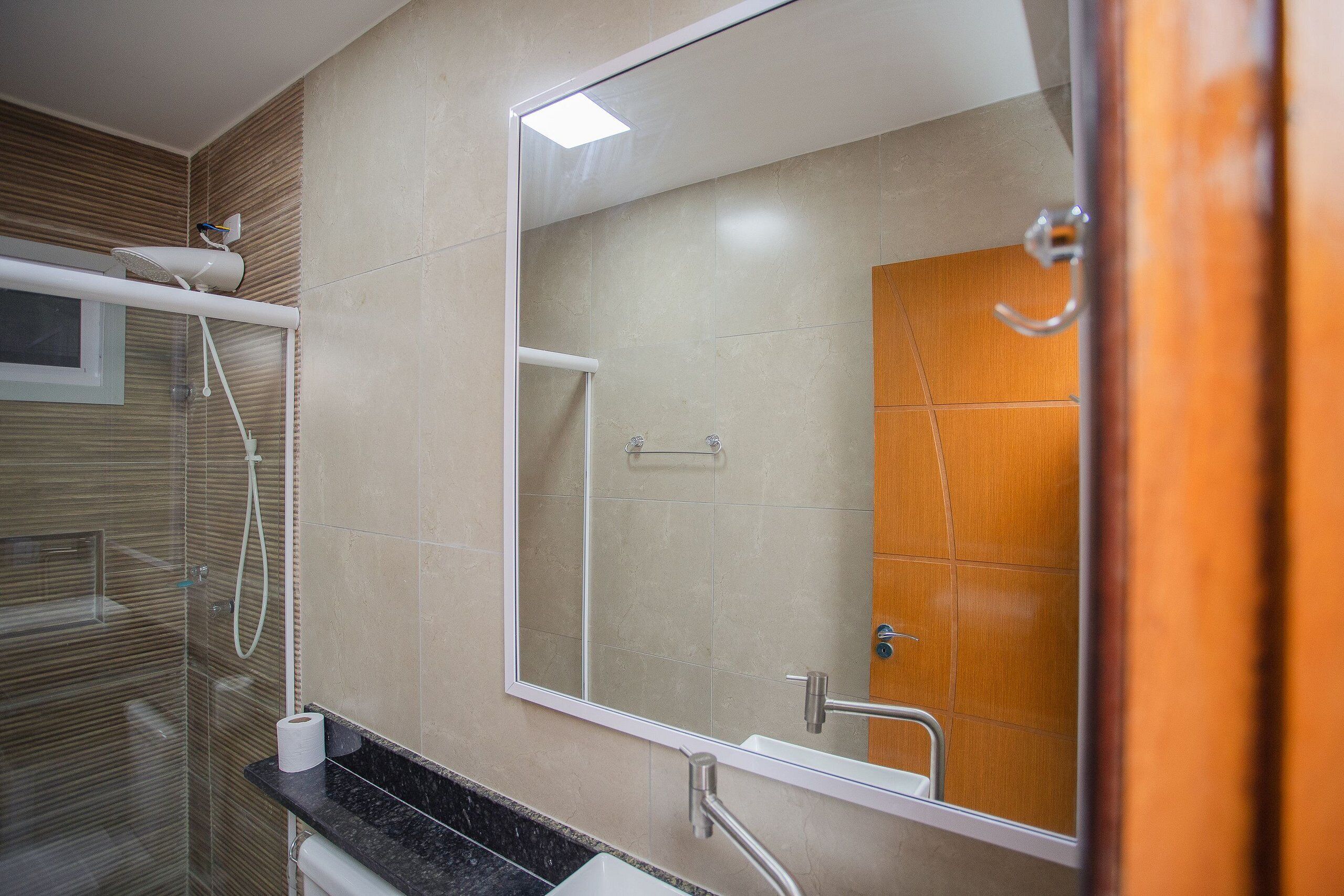Een moderne badkamer met een grote spiegel, een douche en een toilet.