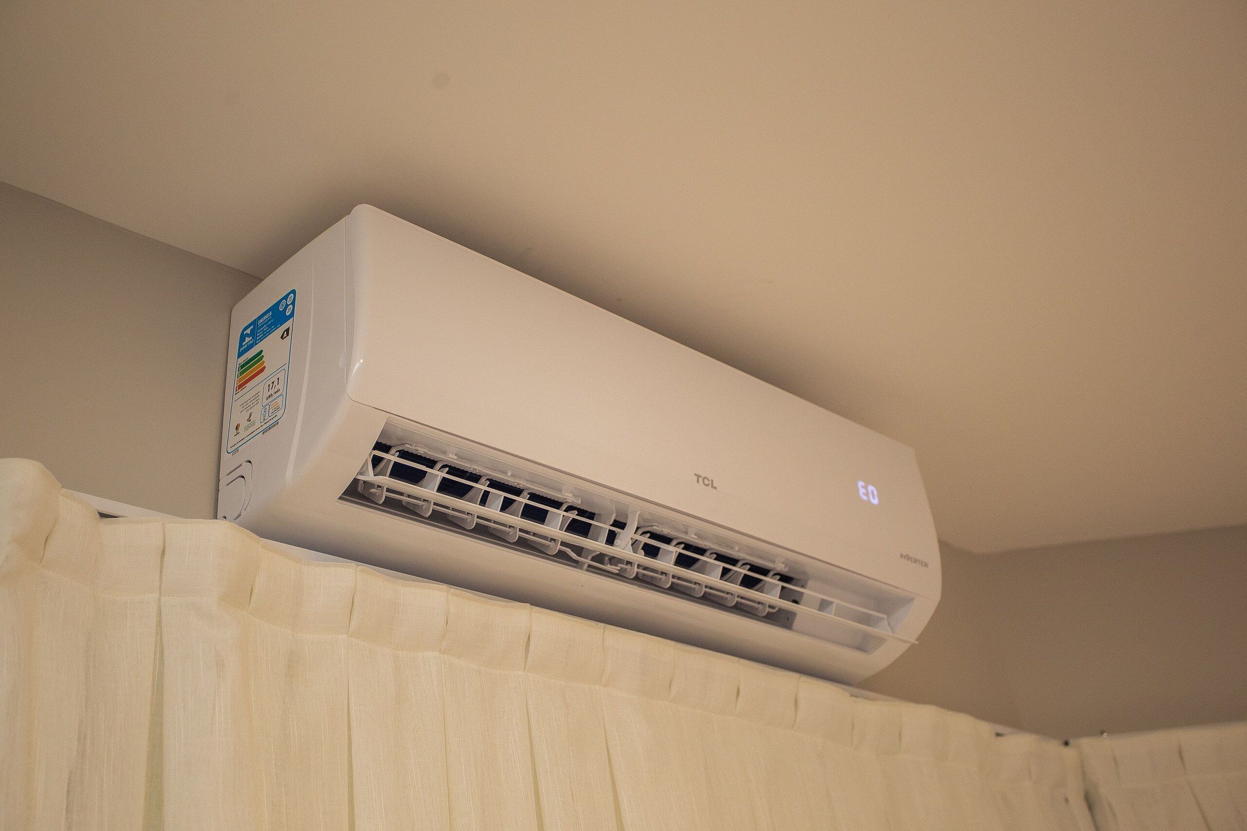 A white air conditioning unit mounted on a wall with a control panel on the left side.