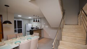 Una cocina moderna con comedor, una escalera y vista al salón.