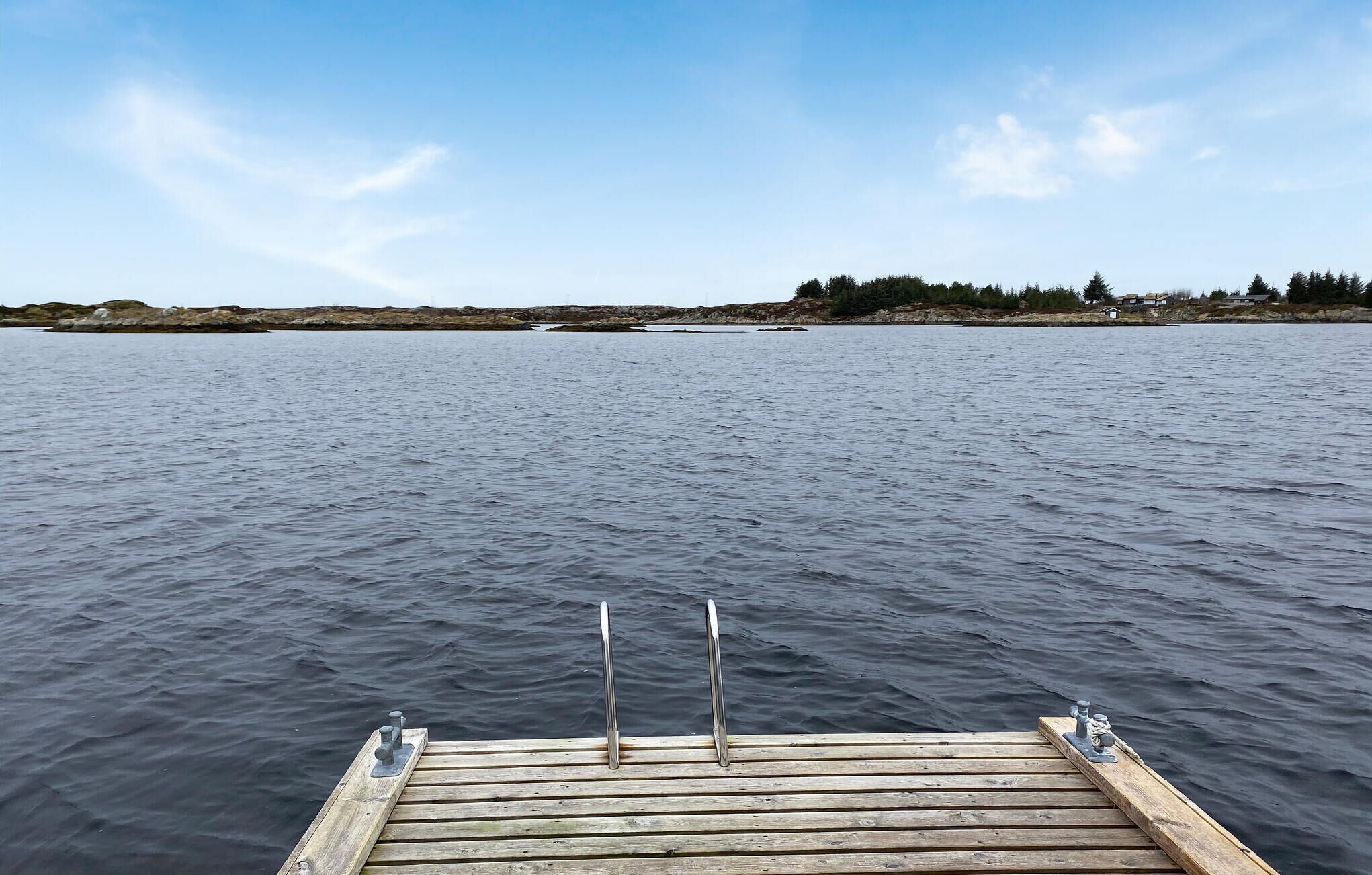 Een houten steiger die uitstelt in kalm water, met een heldere lucht erboven.