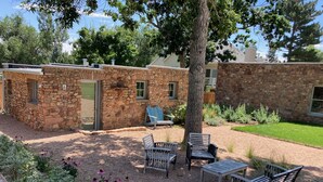 A stone building with a covered patio area, outdoor seating, and a well-maintained garden.