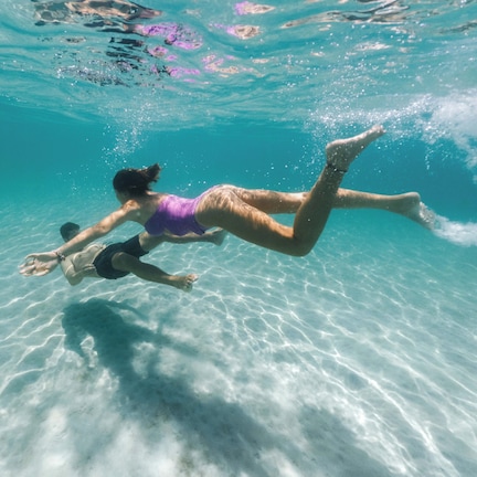 A person swimming underwater in clear blue water.