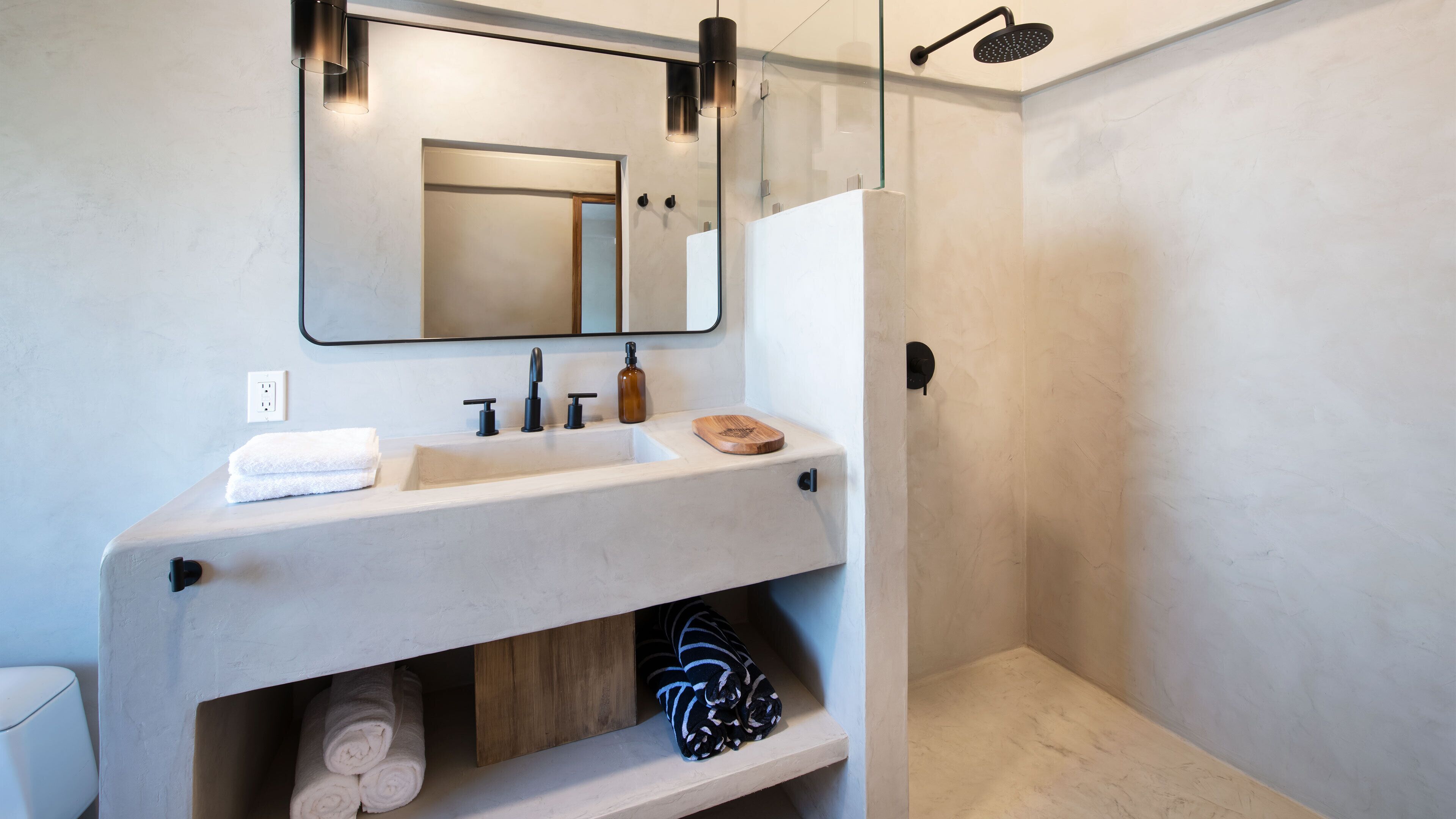 A modern bathroom with a large mirror, a sink, and a shower.
