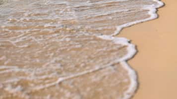 A close-up of a sandy beach with gentle waves lapping at the shore.