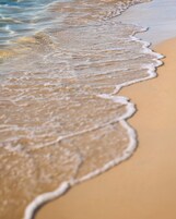 Primer plano de una playa arenosa con olas suaves lamiendo la orilla.