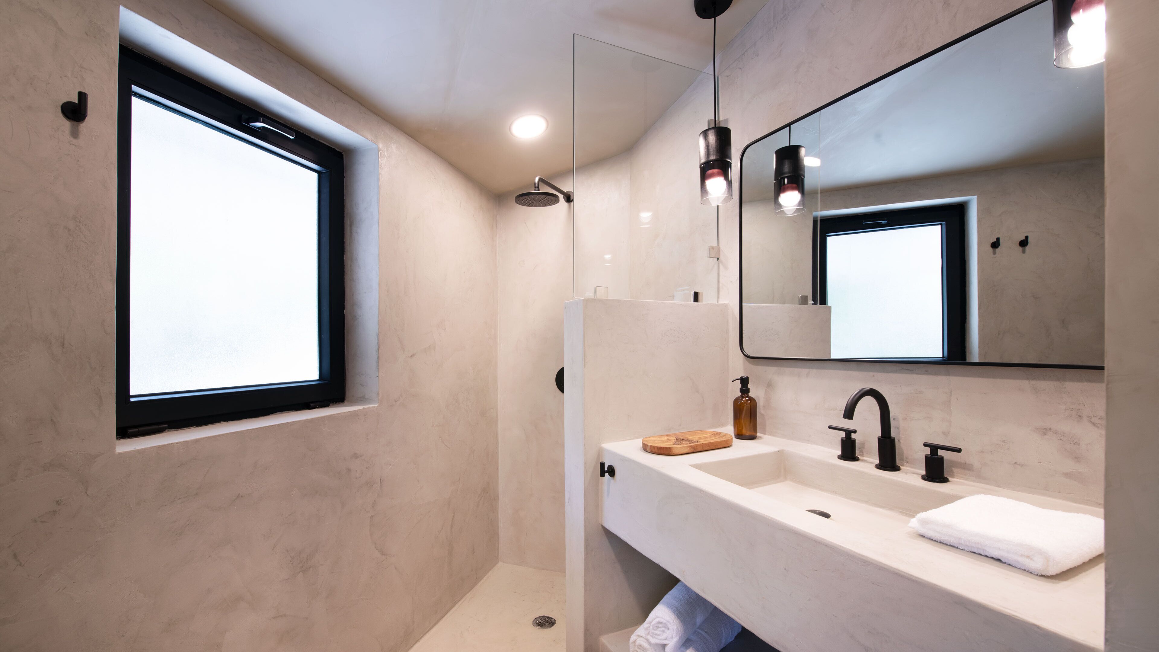 Une salle de bain moderne dotée d’une grande fenêtre, d’une douche à l’italienne et d’un meuble-lavabo avec un miroir.