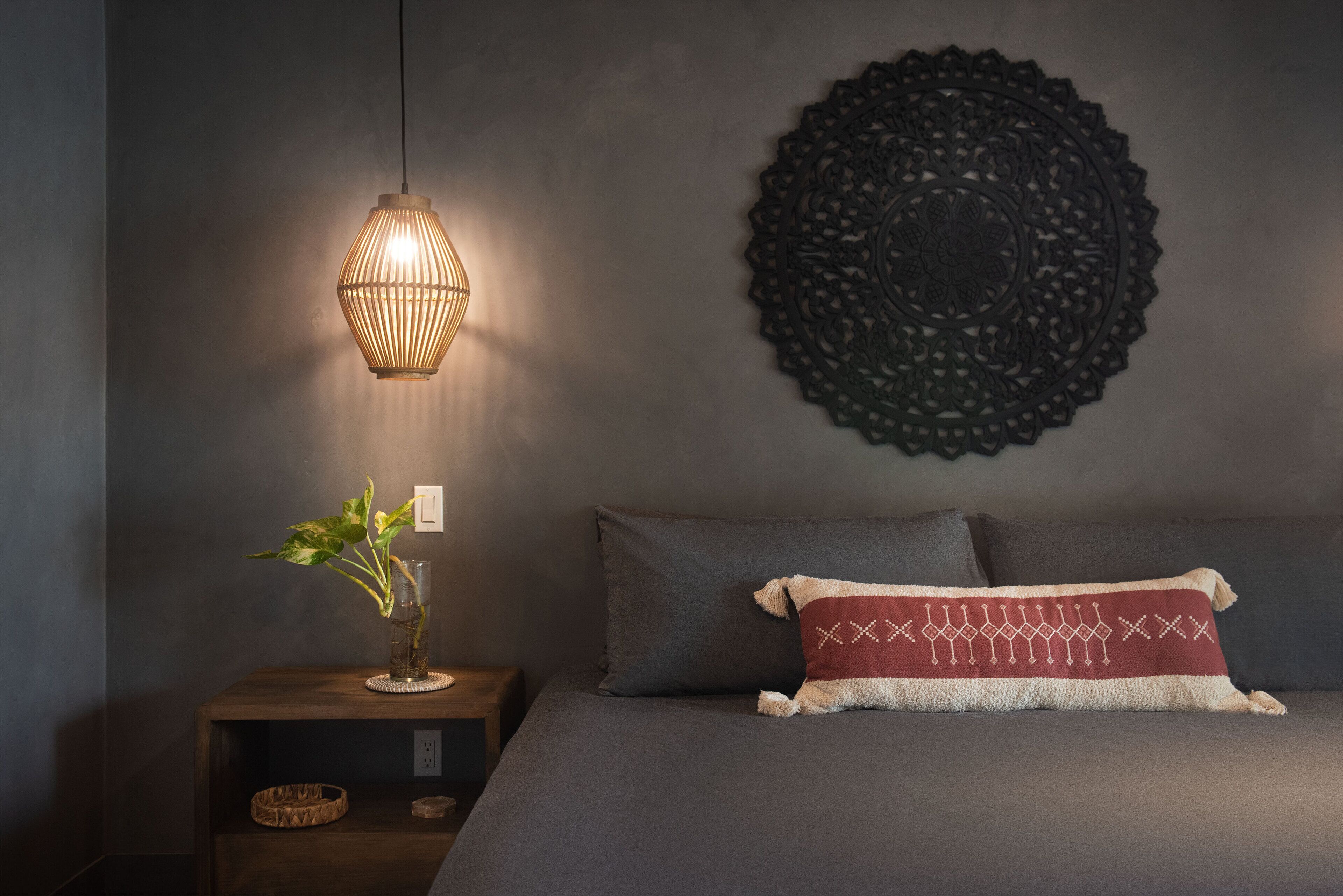Ein Schlafzimmer mit einem Bett, einem Nachttisch, einem Wanddekor und einer Hängelampe.