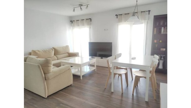 A living room with a sofa, a coffee table, a TV, and a dining table with chairs. - Cozy two bedrooms apartment with terrace (Madrid)