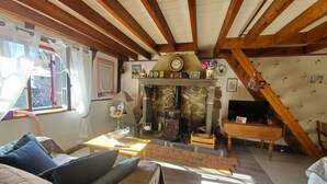 A cozy living room with a stone fireplace, wooden beams, and a comfortable sofa.