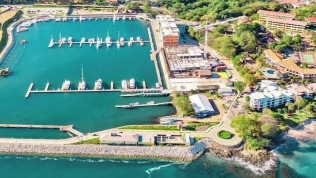 An aerial view of a marina with boats docked, surrounded by greenery and buildings. - Massai Apartments #4 sleeps 5 (Playa Flamingo)