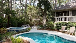 A swimming pool with a hot tub, surrounded by lush greenery and a deck with lounge chairs. - Beautiful spacious home close to the beach! (Hilton Head Island)