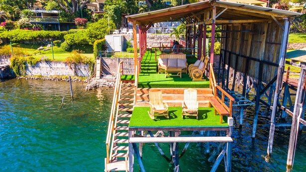 A wooden deck with a covered seating area, a small pool, and a view of the water.