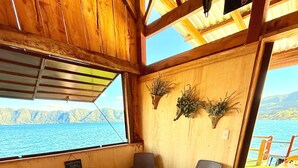 A room with a massage table, a chair, and a view of a lake.