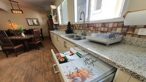 A kitchen with wooden cabinets, a granite countertop, a sink, and a window with a view of the outdoors.