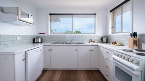 A modern kitchen with white cabinets, a built-in oven, a sink, and a window above the countertop.
