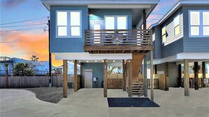 Una casa de dos pisos con balcón, entrada cubierta y terraza de madera.