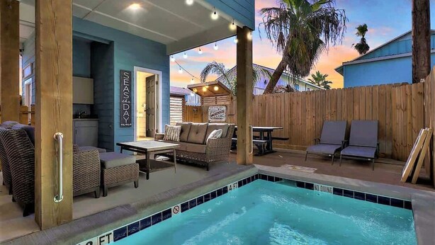 Un área de piscina con sillas de descanso, una mesa y un letrero que dice "SEASDAY".