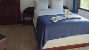 Ein Schlafzimmer mit einem Bett, einem Deckenventilator, einem Fenster und einem Fliesenboden.