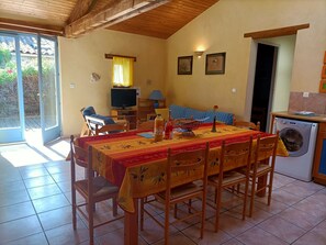 A dining area with a table set for four, a television, and a washing machine in the corner.