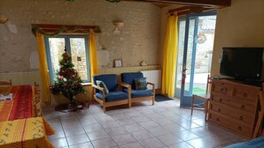 Un saló d'estar acollidor amb un sofà de fusta, dues butaques, un petit arbre de Nadal i una televisió sobre un moble de fusta.