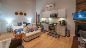 Um espaço compacto com cozinha compacta, sofá, televisão e lareira.