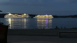 Vista para a orla com dois navios de cruzeiro atracados em um cais.