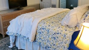 Un dormitori amb un llit, una televisió damunt d'una petita taula, una porta i una làmpada.