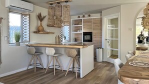 Uma cozinha moderna com uma ilha central, banquetas, uma mesa de jantar e um forno embutido.