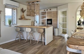 A modern kitchen with a central island, bar stools, a dining table, and a built-in oven. - Amazing home in Vlagtwedde with jacuzzi (Vlagtwedde)