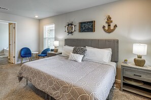 A bedroom with a large bed, a desk, two chairs, a map, and an anchor decoration. - 'Camden Ocean Springs' House Near Beaches! (Ocean Springs)