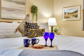 A neatly made bed with a tray of breakfast items, including a cookie and two glasses of blue liquid, possibly juice or water.