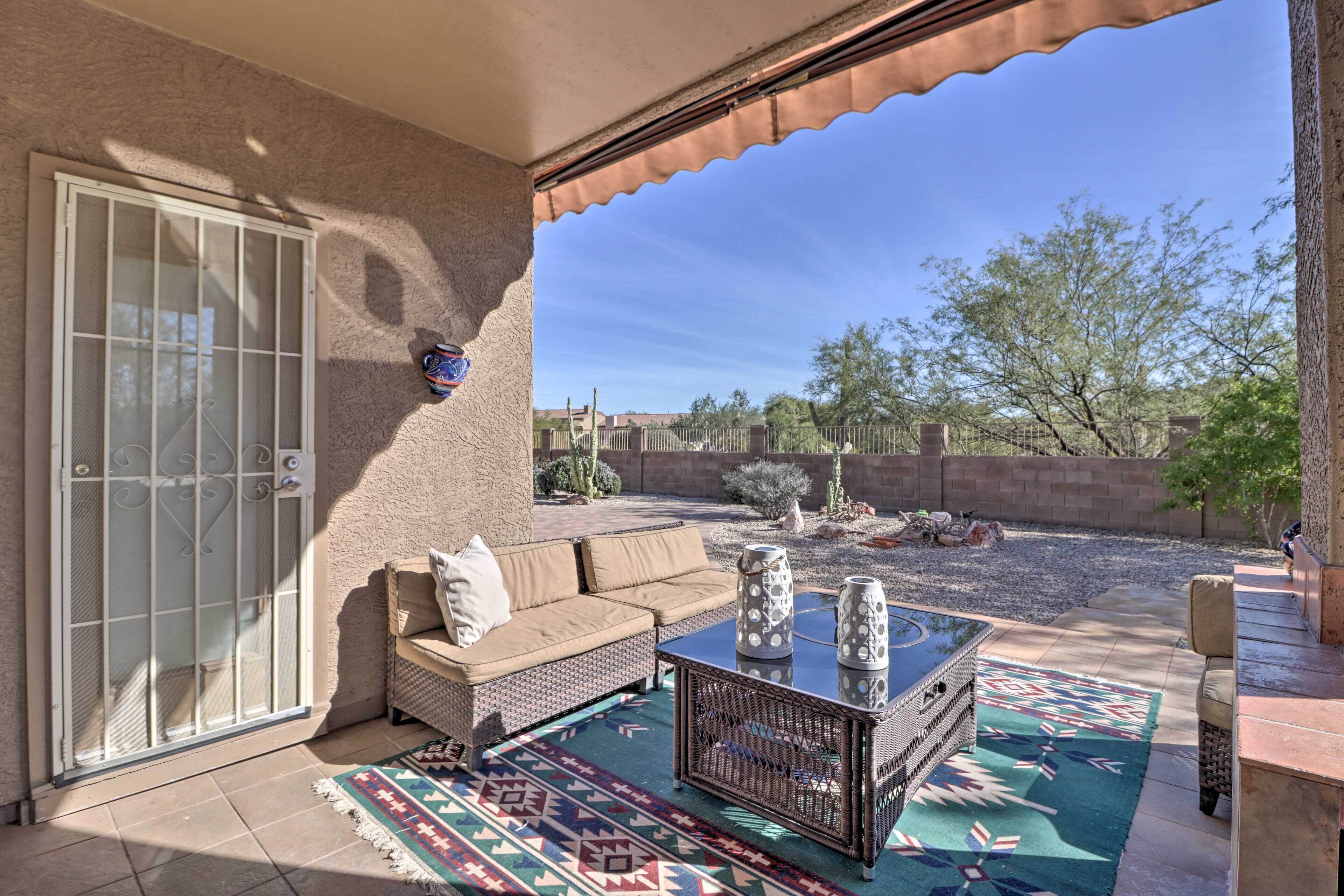 A patio with a sofa, a coffee table, and a patterned rug.