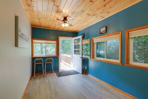 Una stanza con soffitto in legno, ampie finestre e una porta che dà sull'esterno.