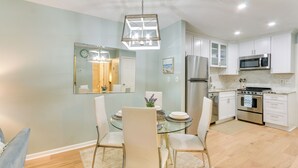 Una cucina moderna con mobili bianchi, elettrodomestici in acciaio inossidabile e un tavolo da pranzo in vetro.