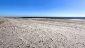 Un'ampia spiaggia sabbiosa con un cielo azzurro limpido.