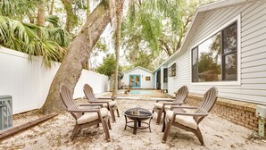 A patio with four chairs and a table, surrounded by a sandy area with trees and a house in the background. - Mt Dora Couple's Retreat w/ Shared Pool! (Mt Dora)