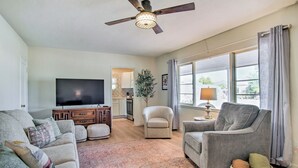 A living room with a sofa, armchairs, a television, a ceiling fan, and a large window with curtains. - Centrally Located Tucson Home ~ 5 Mi to Dtwn! (Tucson)