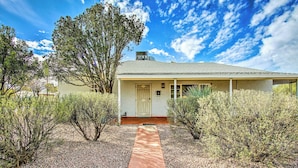 A single-story house with a covered porch, a gravel driveway, and sparse vegetation. - Centrally Located Tucson Home ~ 5 Mi to Dtwn! (Tucson)