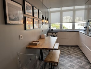 A modern kitchen with a wooden table, clear chairs, and a built-in dishwasher.