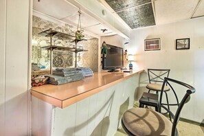 Relax in a serene space with a flat-screen TV, comfortable chair, and a convenient counter with neatly folded towels.