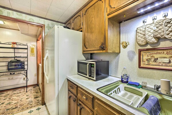 Compact kitchen with a refrigerator, microwave, sink, and toaster oven, offering ample storage in wooden cabinets.