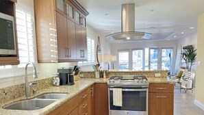 Una cocina moderna con encimeras de granito, electrodomésticos de acero inoxidable, armarios de madera y una isla grande con horno integrado.