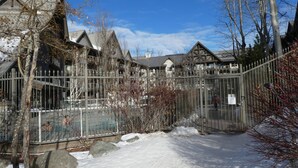 A snow-covered courtyard with a pool, surrounded by buildings with a traditional architectural style. - Ski-in-Out, 3 Hot Tubs & Pool. Re-done unit, in suite Washer/Dryer, Full Kitchen (Whistler)